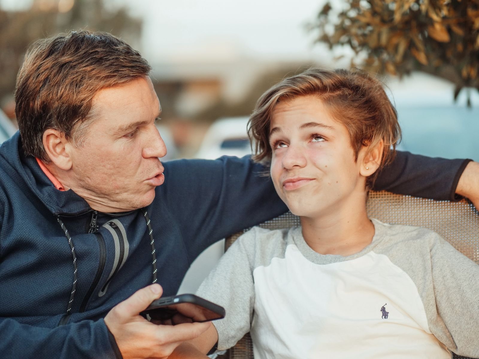 An adult with an arm around a teenage boy, sharing a supportive conversation