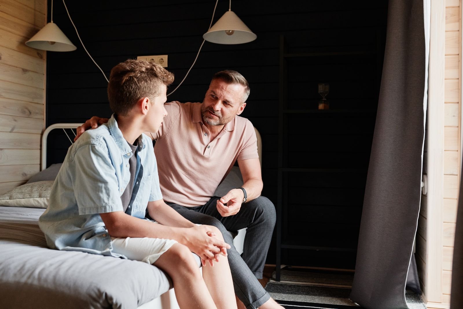 A father and his teenage son sitting together and talking at home