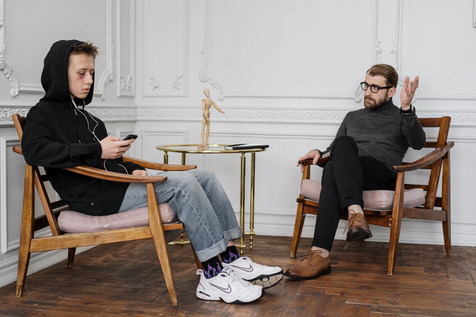 A teenage boy and a counselor sitting across from each other during a conversation