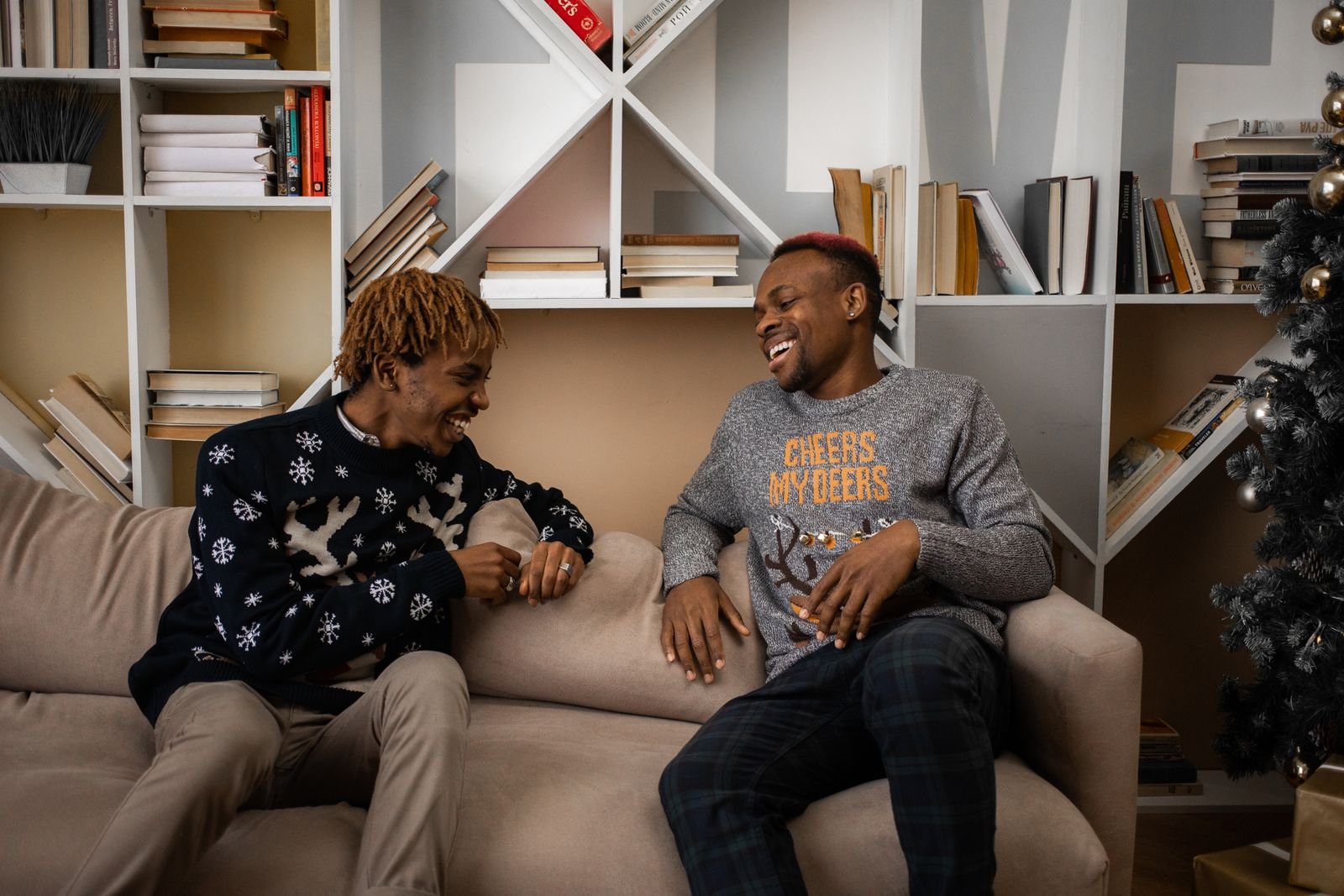 Two young men sitting on a sofa and laughing together in a comfortable living room