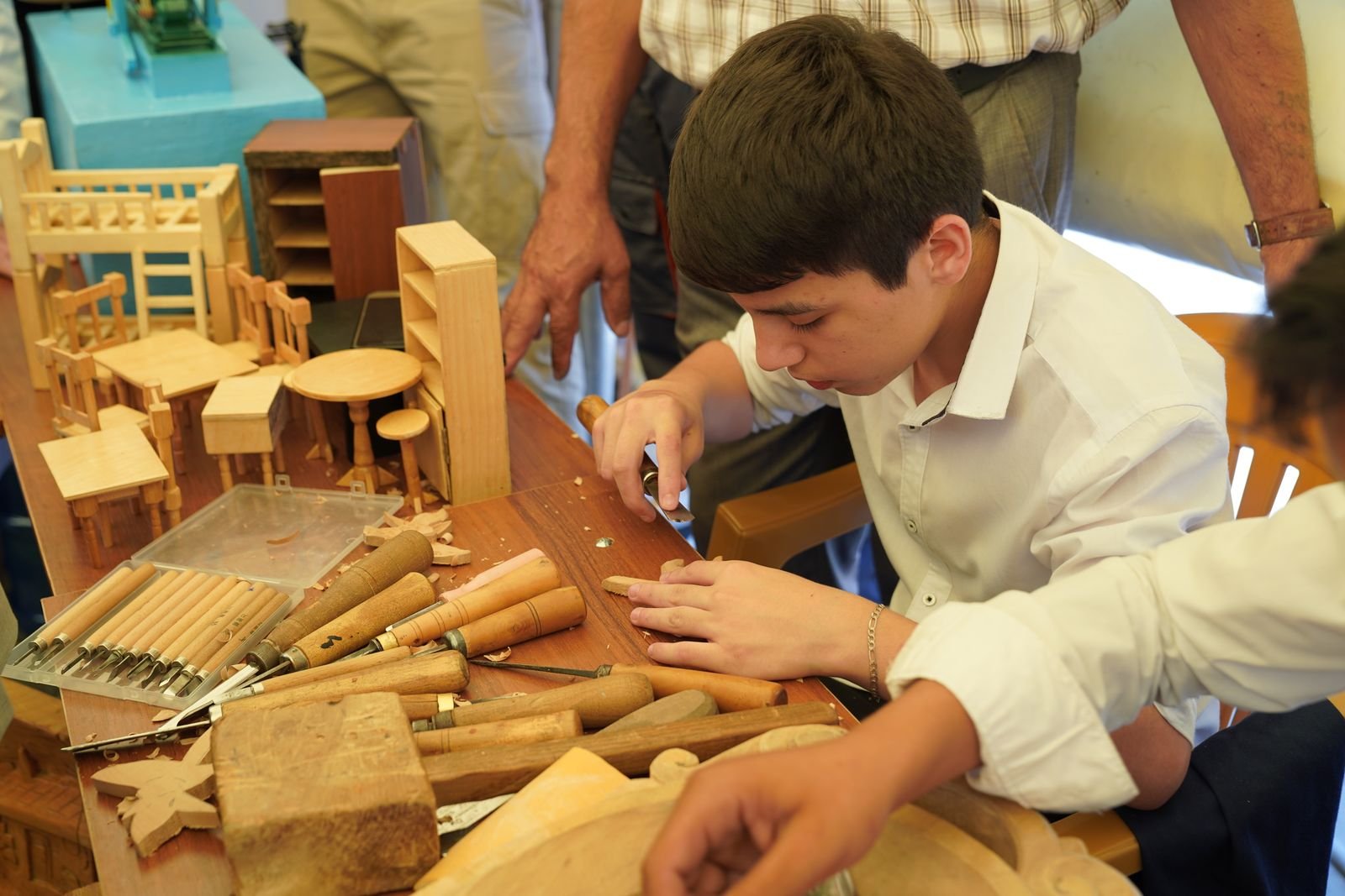 A young man carefully working on a woodworking project at a workbench